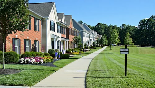 The image depicts a serene suburban neighborhood in Gwinnett County Georgia showcasing a row of wellmaintained singlefamily homes with manicured lawns Each house features a distinct architectural style ranging from traditional brick facades to modern