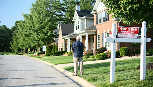 The image depicts a suburban neighborhood in Cobb County showcasing a row of wellmaintained homes with manicured lawns In the foreground a homeowner stands on their driveway holding a clipboard and looking thoughtfully at their house which features a-1