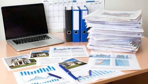 The image depicts a wellorganized workspace filled with property tax appeal documentation In the foreground there are several stacked folders and binders labeled with categories like Comparable Sales Data Property Inspection Reports and Assessment Co