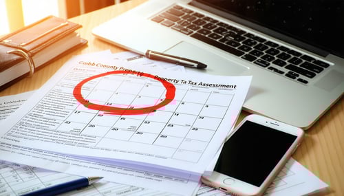 The image showcases a closeup of a calendar page marked with a bright red circle around a specific date indicating a crucial deadline The background features an open laptop displaying a government website with a visible section titled Cobb County Pro-1